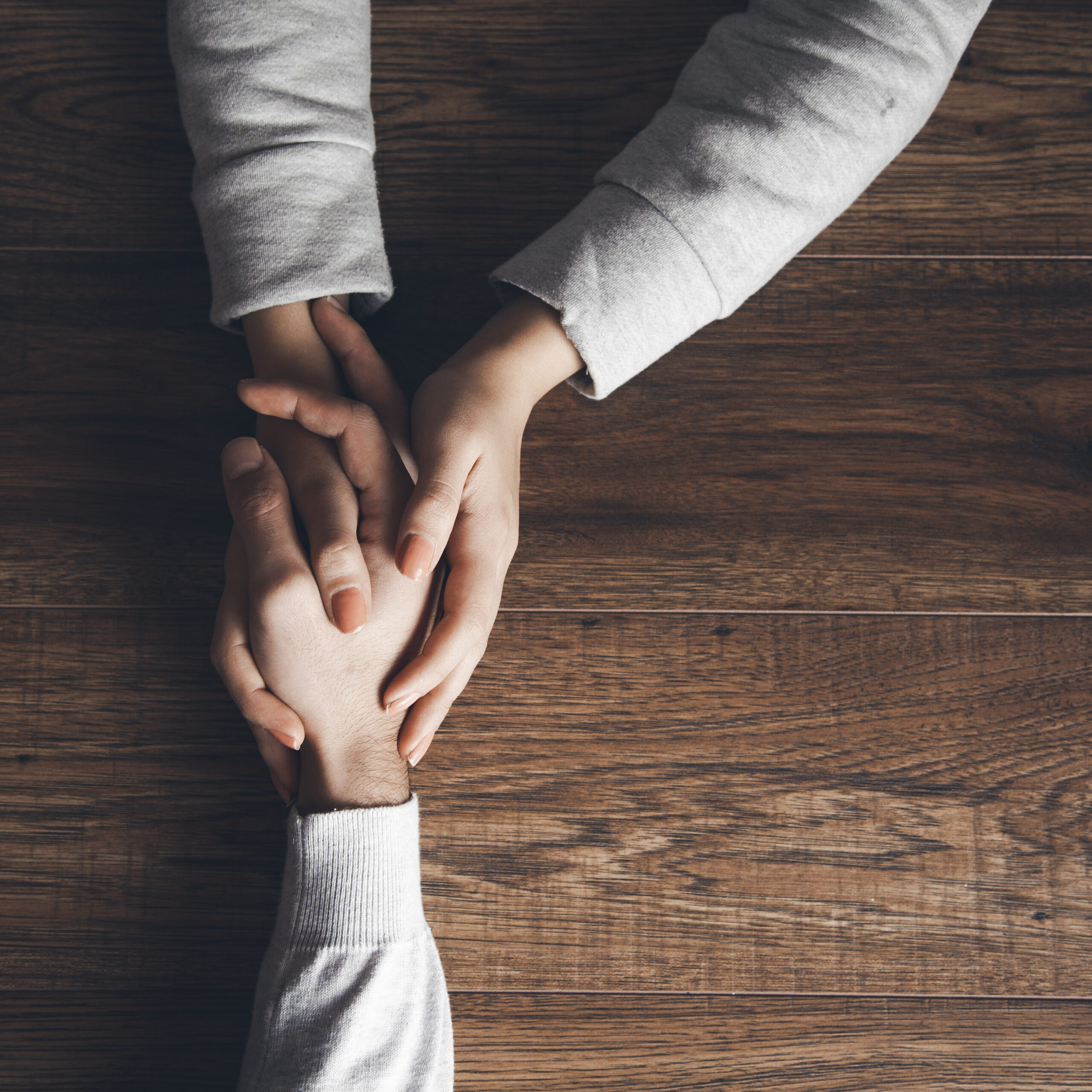 Two people holding hands, symbolizing resolving workplace conflicts using Instinctual Variants